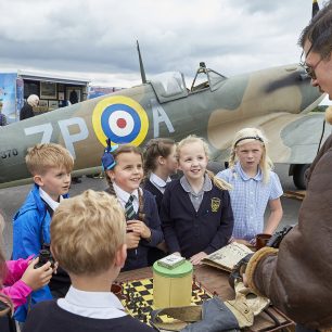 Children handle artefacts, including an old chess set, and chat with one of the re-enactors